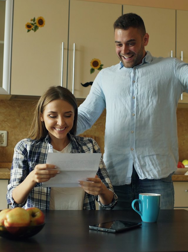 A couple reading an offer letter at their kitchen table